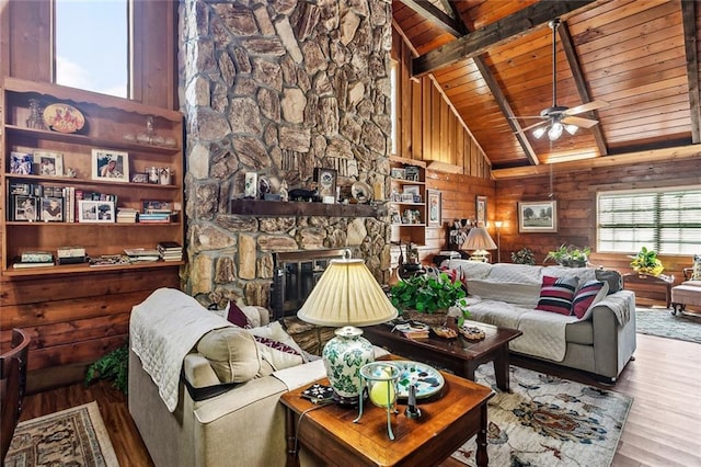 living area with a ceiling fan, vaulted ceiling with beams, wooden ceiling, and wood finished floors