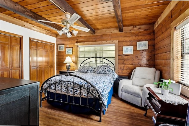 bedroom with wooden ceiling, beam ceiling, multiple windows, and wood finished floors