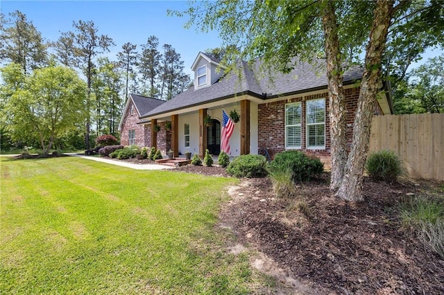 cape cod home with a porch, a front yard, brick siding, fence, and a shingled roof