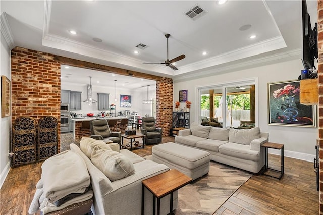 living area with crown molding, ceiling fan, a tray ceiling, and visible vents
