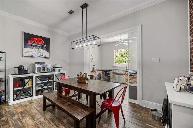 dining room featuring crown molding, dark wood-style flooring, ceiling fan, baseboards, and visible vents