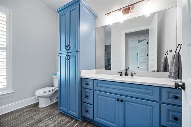 bathroom with toilet, baseboards, wood finished floors, and vanity