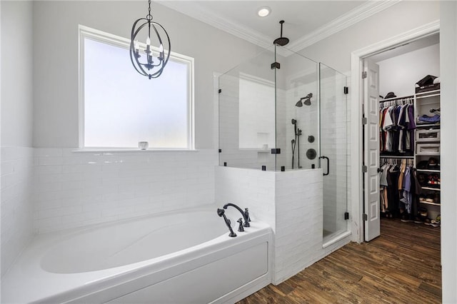 bathroom with a walk in closet, a bath, a shower stall, an inviting chandelier, and ornamental molding
