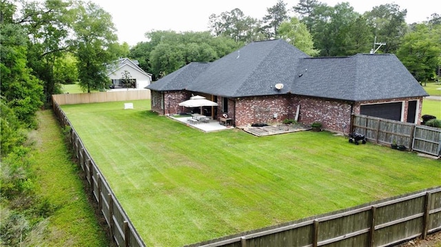 view of yard with a garage, a fenced backyard, and a patio area