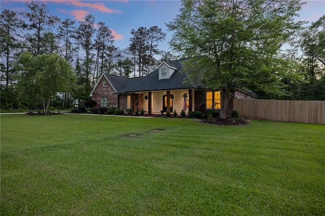 cape cod-style house with fence, a porch, and a front yard
