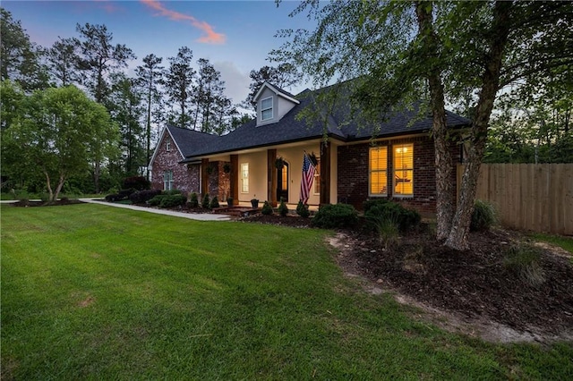 new england style home with brick siding, fence, and a front yard