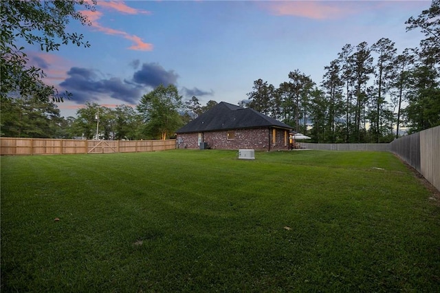 yard at dusk featuring a fenced backyard