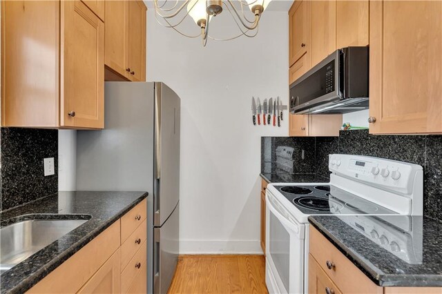 4716 Annunciation St Unit 2E, New Orleans, LA 70115 - kitchen featuring a notable chandelier, light wood finished floors, stainless steel appliances, baseboards, and backsplash