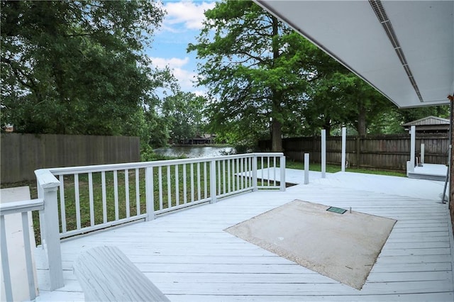 wooden deck featuring a lawn, a water view, and a fenced backyard
