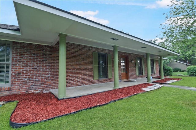 back of house featuring covered porch, a yard, and brick siding