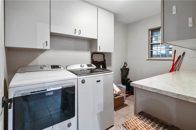 clothes washing area with light tile patterned floors, independent washer and dryer, and cabinet space