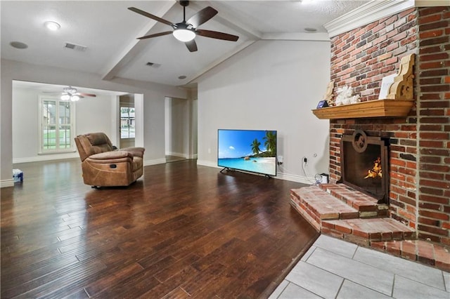 living area with ceiling fan, a brick fireplace, baseboards, wood finished floors, and visible vents