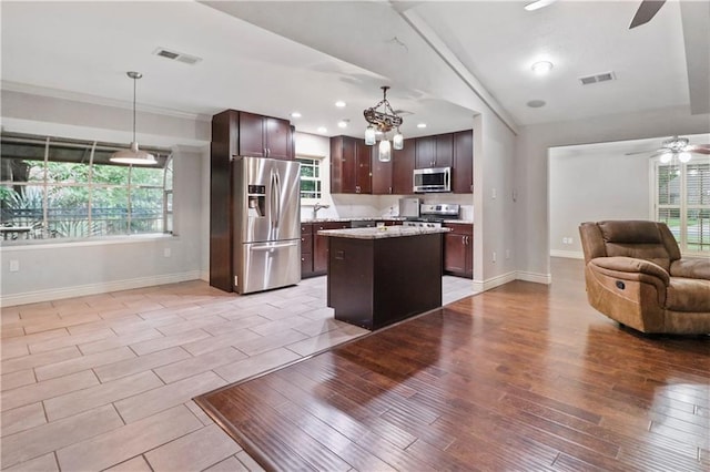 kitchen with ceiling fan with notable chandelier, stainless steel appliances, open floor plan, baseboards, and visible vents