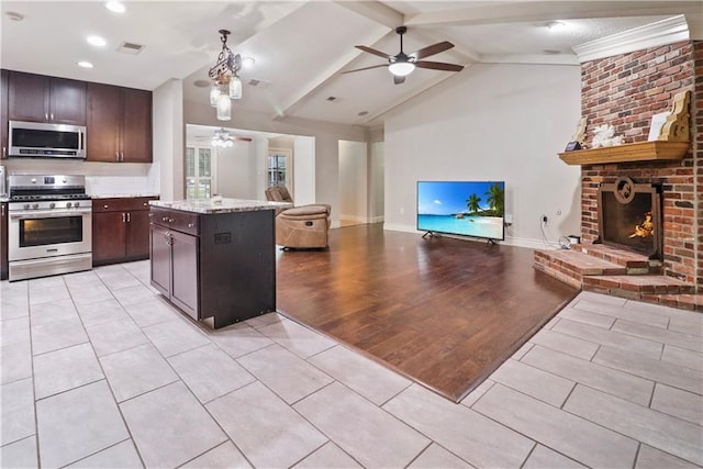 kitchen with appliances with stainless steel finishes, lofted ceiling with beams, a ceiling fan, and open floor plan