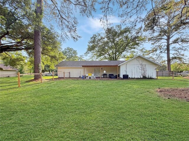 rear view of house featuring a lawn, board and batten siding, fence, and central AC