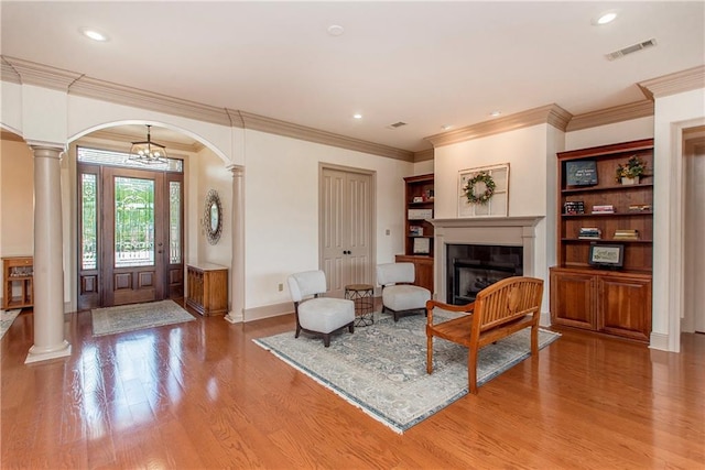 14208 W Hoffman Rd, Hammond, LA 70403 - living room with arched walkways, decorative columns, a glass covered fireplace, and light wood-style floors