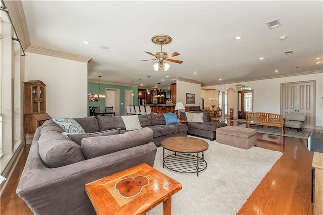 14208 W Hoffman Rd, Hammond, LA 70403 - living room featuring visible vents, ornamental molding, wood finished floors, arched walkways, and ceiling fan with notable chandelier