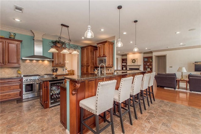 14208 W Hoffman Rd, Hammond, LA 70403 - kitchen with wall chimney range hood, appliances with stainless steel finishes, wine cooler, visible vents, and stone tile flooring