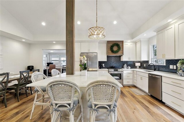 kitchen with vaulted ceiling, stainless steel appliances, a kitchen bar, and a wealth of natural light