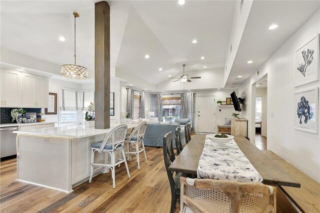 kitchen with stainless steel dishwasher, lofted ceiling, recessed lighting, light countertops, and white cabinets