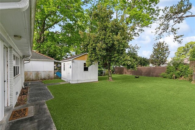 view of yard featuring a fenced backyard, a shed, and an outbuilding