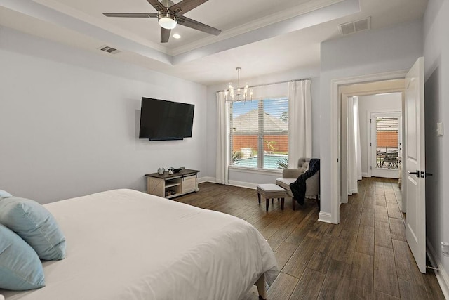 bedroom with visible vents, dark wood-style flooring, crown molding, and a tray ceiling