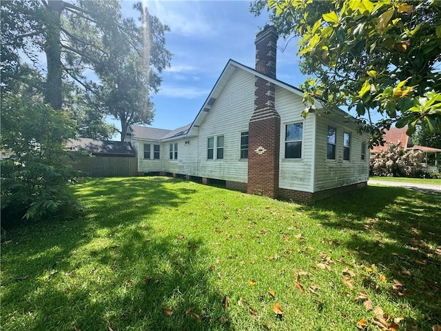back of property with a yard, fence, and a chimney