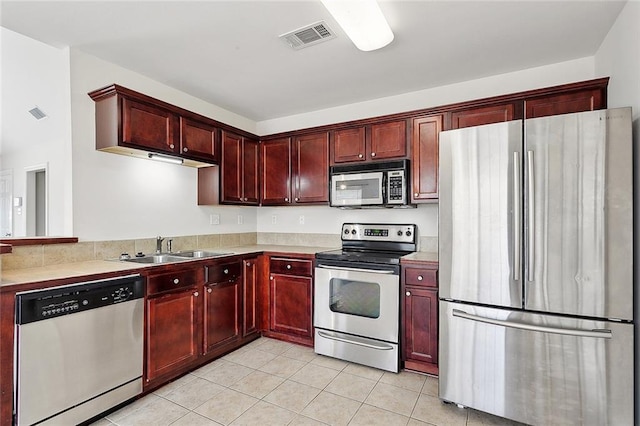 70363 10th St, Covington, LA 70433 - kitchen featuring visible vents, a sink, light tile patterned floors, reddish brown cabinets, and stainless steel appliances