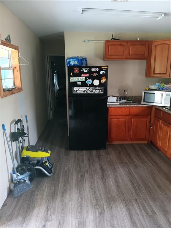 kitchen featuring freestanding refrigerator, dark wood-style flooring, and brown cabinets