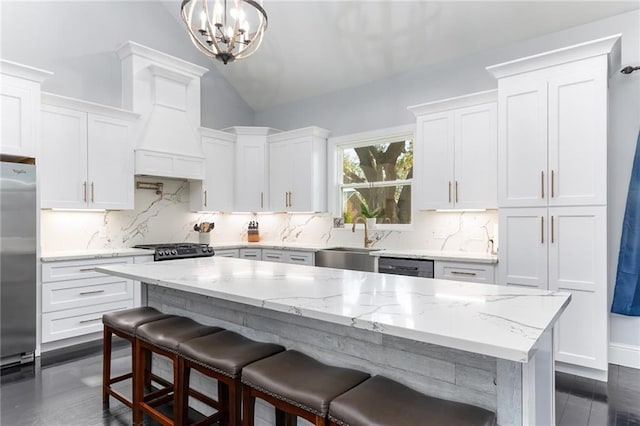 kitchen featuring stainless steel refrigerator, stove, tasteful backsplash, a sink, and vaulted ceiling