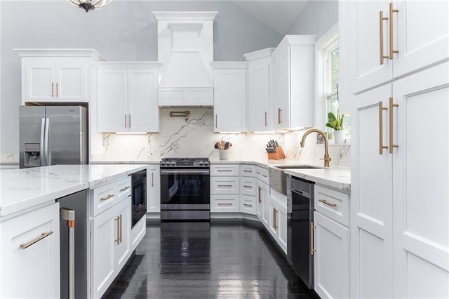 kitchen featuring light stone countertops, white cabinets, tasteful backsplash, a sink, and appliances with stainless steel finishes