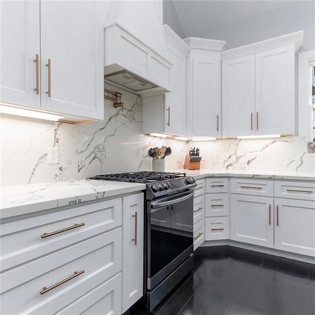 kitchen featuring decorative backsplash, gas range, light stone countertops, premium range hood, and white cabinetry