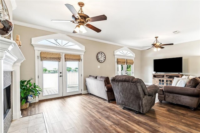 living area featuring a fireplace, french doors, a ceiling fan, wood finished floors, and ornamental molding