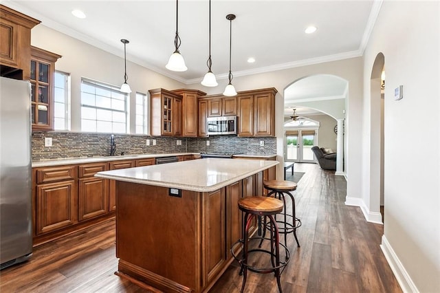 kitchen featuring brown cabinetry, appliances with stainless steel finishes, tasteful backsplash, and a center island