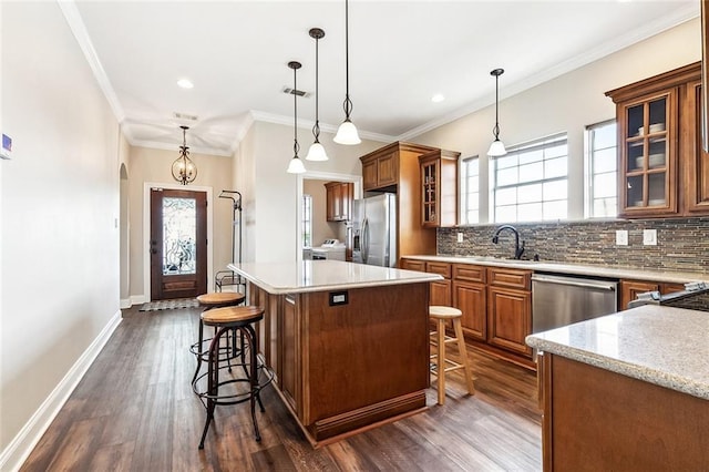 kitchen with a sink, appliances with stainless steel finishes, a breakfast bar area, and brown cabinets