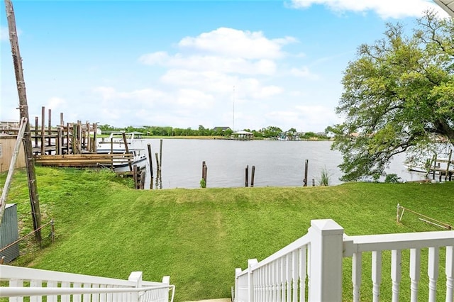 view of dock with a lawn and a water view