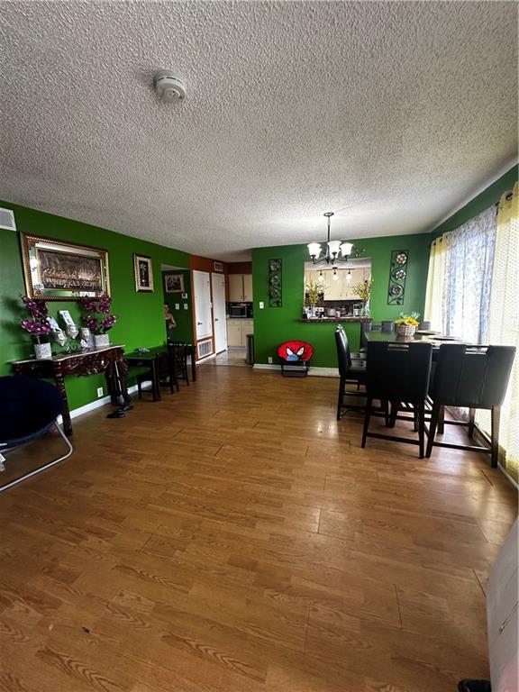 6320 Riverside Dr Unit 350, Metairie, LA 70003 - dining space with a textured ceiling, wood finished floors, and a notable chandelier