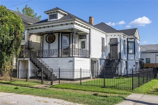 shotgun-style home featuring stairs, a fenced front yard, covered porch, and a front yard