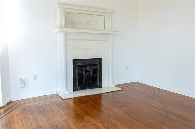 interior details with baseboards, a brick fireplace, and wood finished floors