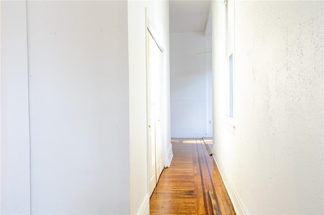 corridor with baseboards and wood finished floors