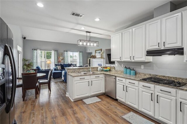 kitchen with gas cooktop, visible vents, stainless steel dishwasher, a sink, and freestanding refrigerator
