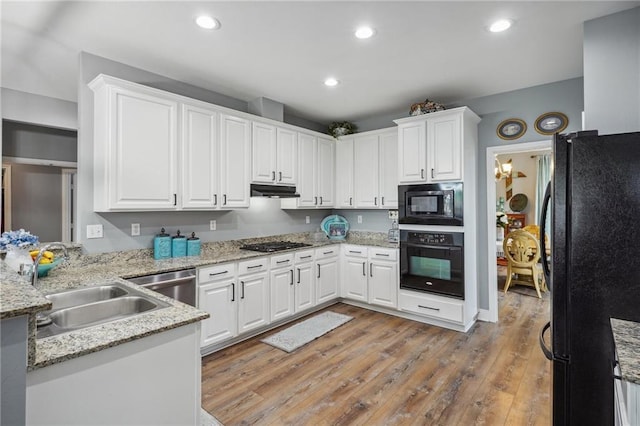 kitchen with a sink, white cabinets, black appliances, and under cabinet range hood