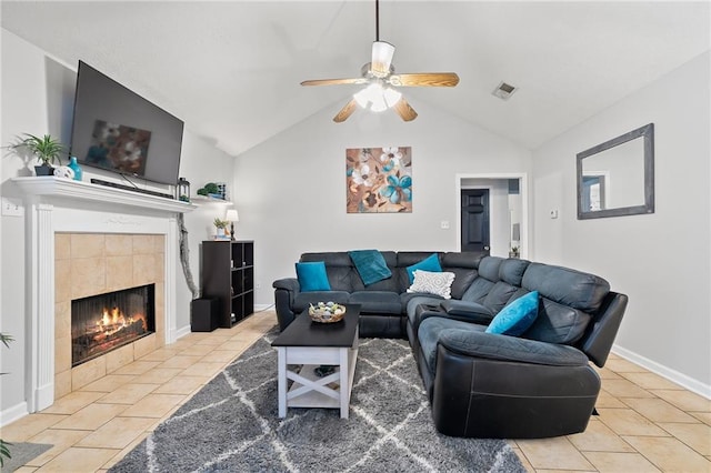 living room with baseboards, tile patterned floors, a tiled fireplace, a ceiling fan, and vaulted ceiling
