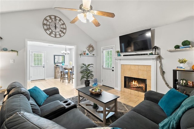 living room with plenty of natural light, light tile patterned floors, ceiling fan with notable chandelier, and a tiled fireplace
