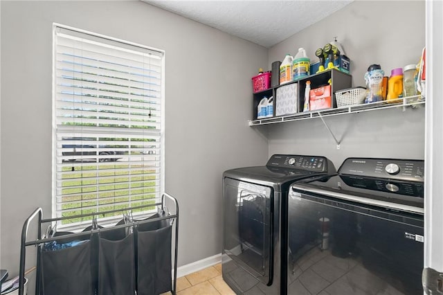 clothes washing area featuring light tile patterned floors, laundry area, a textured ceiling, and washer and dryer