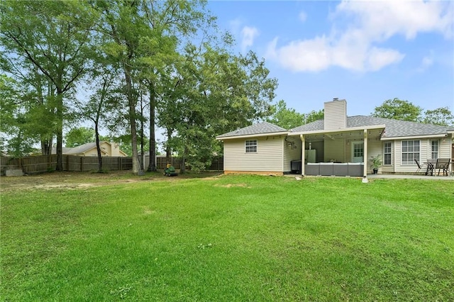 back of house featuring a chimney, roof with shingles, a lawn, a fenced backyard, and a patio