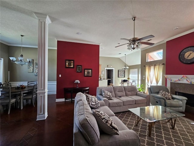 living room with a textured ceiling, ceiling fan with notable chandelier, decorative columns, lofted ceiling, and ornamental molding