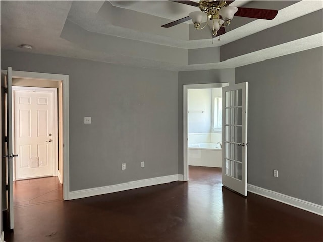 spare room featuring baseboards, ceiling fan, and a raised ceiling