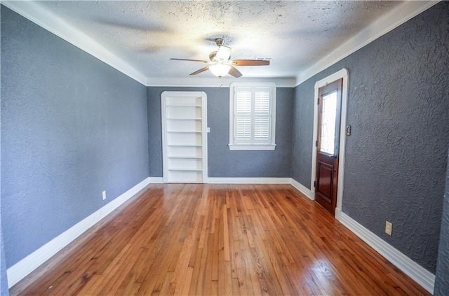 3220 48th St, Metairie, LA 70001 - empty room with hardwood / wood-style floors, a textured ceiling, a textured wall, and built in shelves