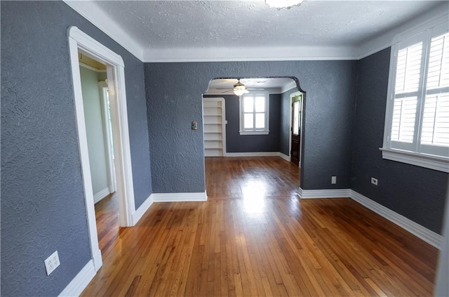 3220 48th St, Metairie, LA 70001 - unfurnished room featuring wood-type flooring, arched walkways, a textured wall, and a textured ceiling